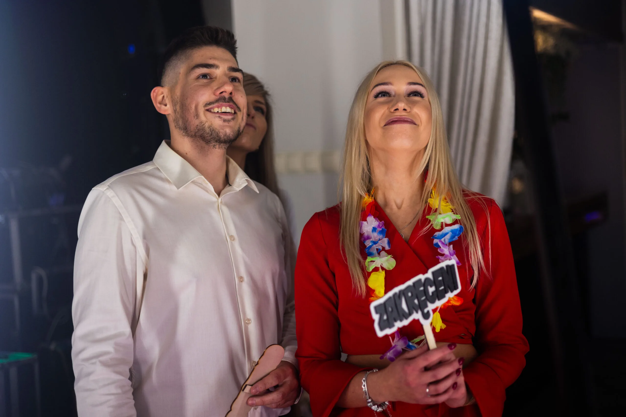 Roześmiana para z rekwizytami czeka na swój obrót wideobudki na weselu